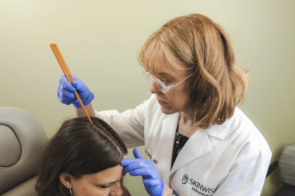 Provider examining a patient's scalp during a hair loss evaluation